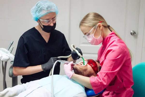 Profesjonalne czyszczenie zębów. Dentysta myje zęby męskiemu pacjentowi. — Zdjęcie stockowe