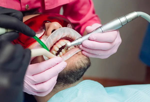 Professional teeth cleaning. Dentist cleans the teeth of a male patient.