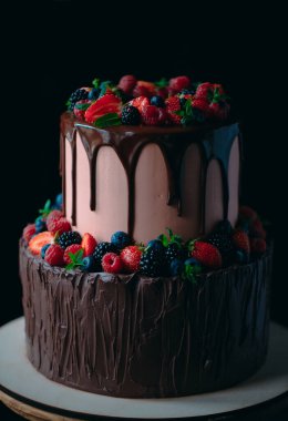 Tahta üzerinde meyveli çikolatalı kek siyah arka planda duruyor..