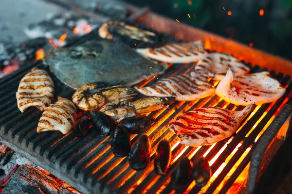 Fruits de mer sur le gril. Moules, crevettes, calmars et poissons sont cuits au feu. — Photo