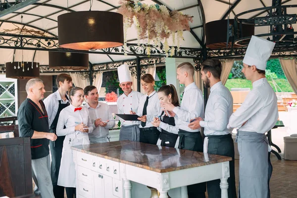 Restaurant manager and his staff in terrace. interacting to head chef in restaurant.