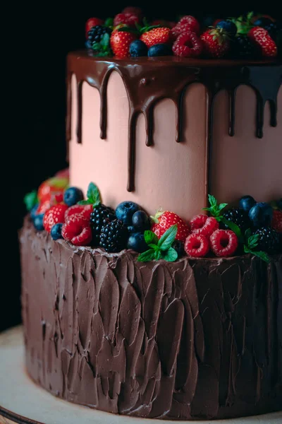 Bolo de chocolate de frutas no carrinho de madeira no fundo preto. — Fotografia de Stock