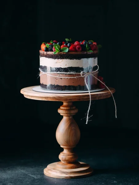 Meyveli kek. Kek, siyah arka plandaki ahşap bir stantta böğürtlenlerle süslenmiş.. — Stok fotoğraf