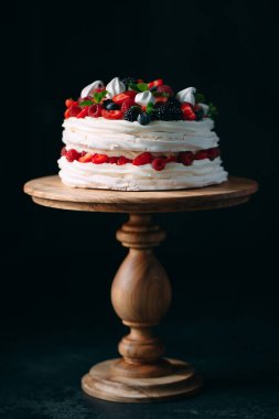 Meyveli kek. Kek, siyah arka plandaki ahşap bir stantta böğürtlenlerle süslenmiş..