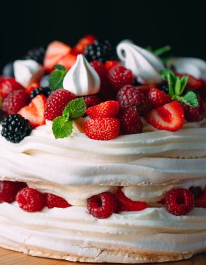 Meyveli kek. Kek, siyah arka plandaki ahşap bir stantta böğürtlenlerle süslenmiş..