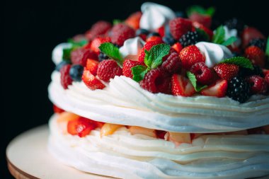 Meyveli kek. Kek, siyah arka plandaki ahşap bir stantta böğürtlenlerle süslenmiş..