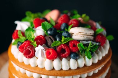 Meyveli kek. Kek, siyah arka plandaki ahşap bir stantta böğürtlenlerle süslenmiş..