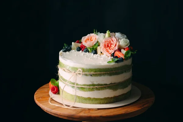 Bolo é decorado com flores em um fundo escuro. — Fotografia de Stock