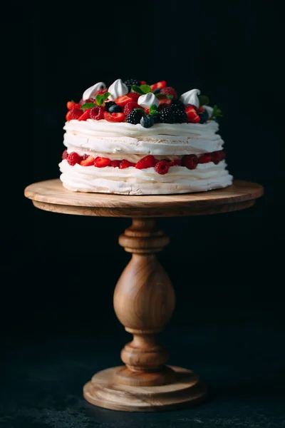 Gyümölcstorta. Torta díszített bogyók egy fa stand egy fekete háttér. — Stock Fotó