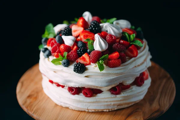 Fruit cake. Cake decorated with berries on a wooden stand on a black background. — Stock Photo, Image