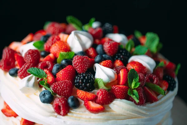 Pastel de frutas. Pastel decorado con bayas en un soporte de madera sobre un fondo negro. — Foto de Stock