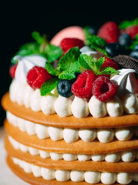 Pastel de frutas. Pastel decorado con bayas en un soporte de madera sobre un fondo negro. — Foto de Stock