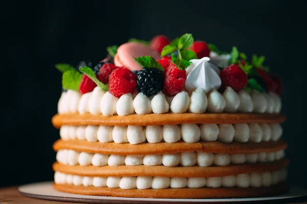 Pastel de frutas. Pastel decorado con bayas en un soporte de madera sobre un fondo negro. — Foto de Stock