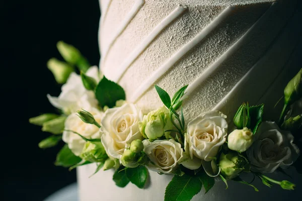 Bolo é decorado com flores em um fundo escuro. — Fotografia de Stock