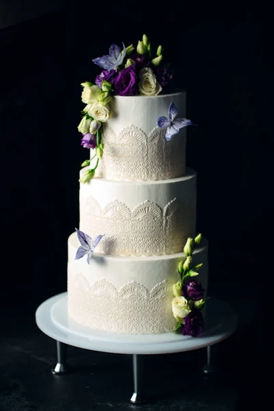 Bolo é decorado com flores em um fundo escuro. — Fotografia de Stock