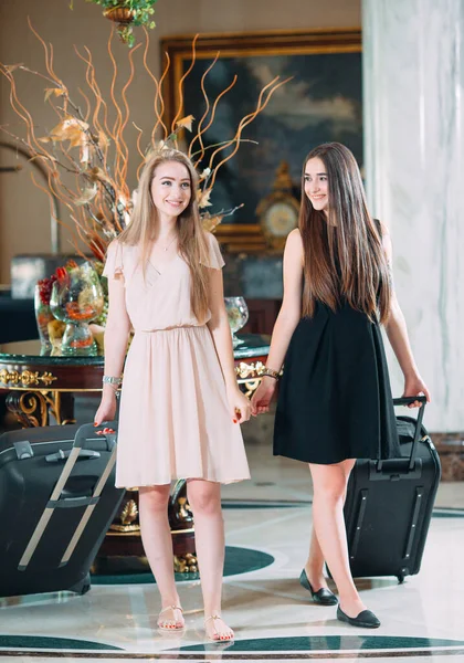 Молодые девушки возле стойки регистрации в отеле. Молодые девушки приходят в отель. — стоковое фото