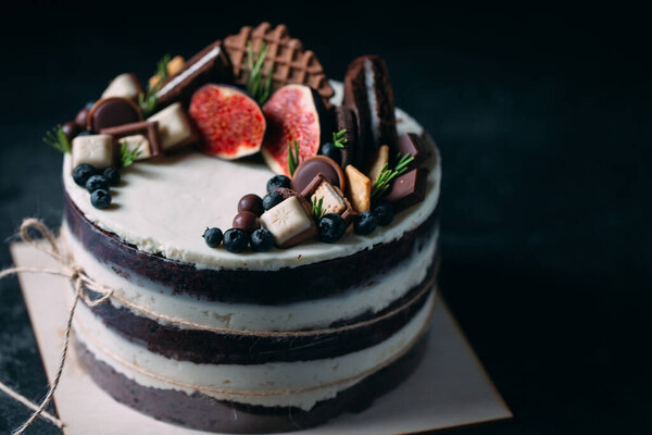 Fruit cake decorated with figs, cookies and blueberries.