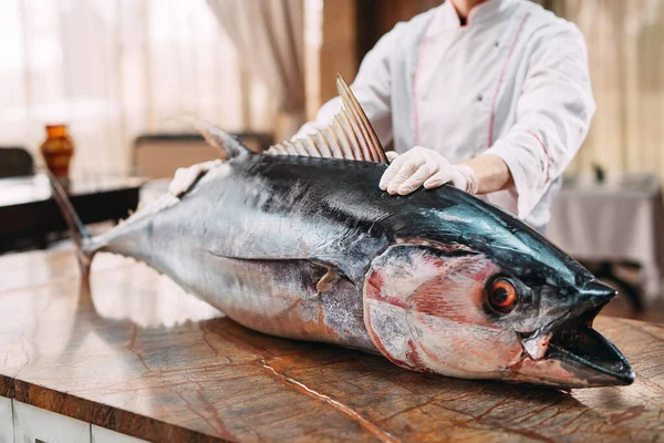 The chef cut up a big Tuna fish in the restaurant.