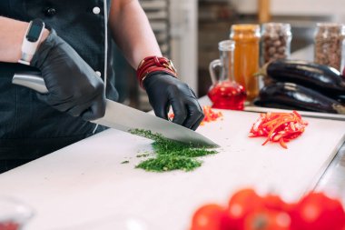 Bir kadın şef bir restoranda mutfakta sebze doğruyor..