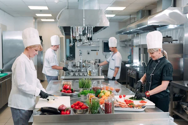 Kockar skär grönsaker i restaurangköket. — Stockfoto