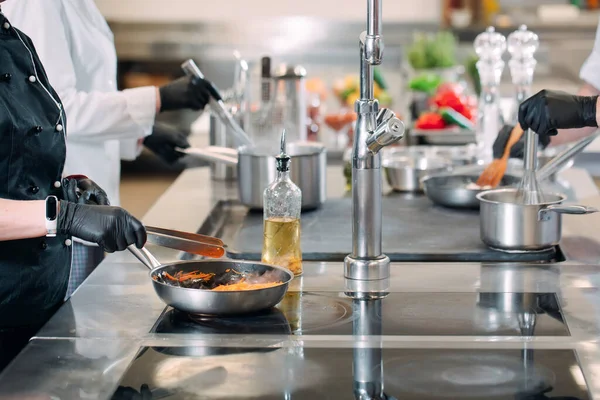 Aşçılar, restoranda ya da otelde profesyonel bir mutfakta elektrikli ocakta yemek hazırlarlar.. — Stok fotoğraf