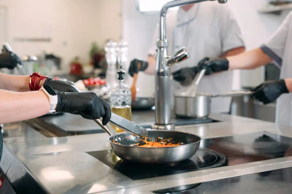 Повара готовят блюда на электрической плите на профессиональной кухне в ресторане или отеле. — стоковое фото