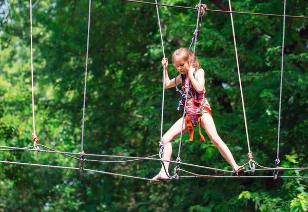Happy školní dívka těší činnost v horolezectví dobrodružství park v letní den, — Stock fotografie