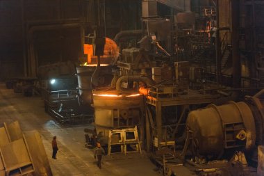 Çelik fabrikasında metalin erimesi. Eriyen ocakta yüksek sıcaklık. Metalürji endüstrisi. Metal borular üreten bir fabrika. Metali kalıplara doldurmak için kova.
