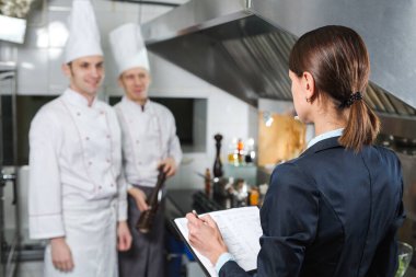 Restoran müdürü, mutfak personeline ticari mutfakta brifing veriyor..