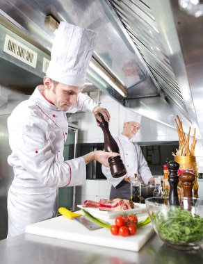 Şef restoranın mutfağında yemek hazırlıyor.