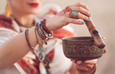 konsept. Tibet kâsesinde oynayan bir kadın. Hamile kadın gün batımında tarlada yoga yapıyor.