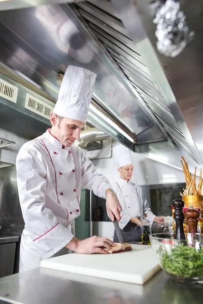 Chef cortando carne na tábua de corte, cozinheiro profissional segurando faca e cortando carne no restaurante. — Fotografia de Stock