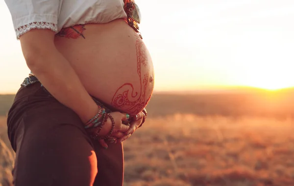 Hamile kadın gün batımında tarlada yoga yapıyor. — Stok fotoğraf