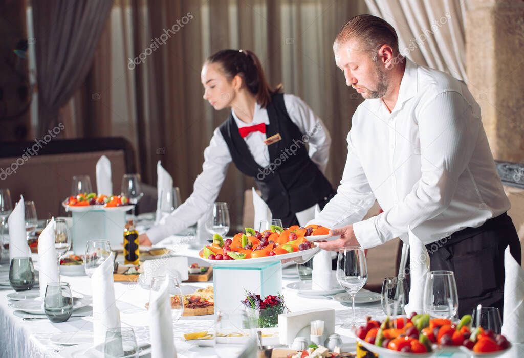 Waiters serving table in the restaurant preparing to receive guests
