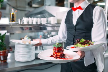 Garson lokantada görev başında. Garson bulaşıkları taşıyor..