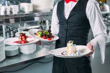 Garson lokantada görev başında. Garson bulaşıkları taşıyor.