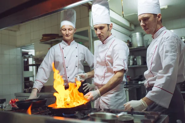 Fuego en la cocina. Quemadura de gas fuego se cocina en la sartén de hierro, revuelva fuego muy caliente — Foto de Stock