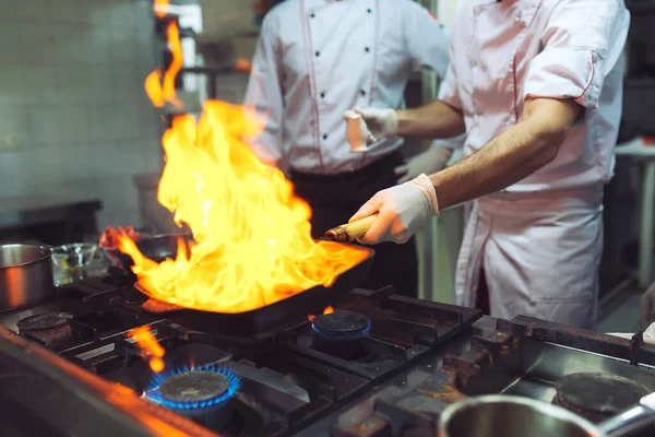 Fuego en la cocina. Quemadura de gas fuego se cocina en la sartén de hierro, revuelva fuego muy caliente — Foto de Stock