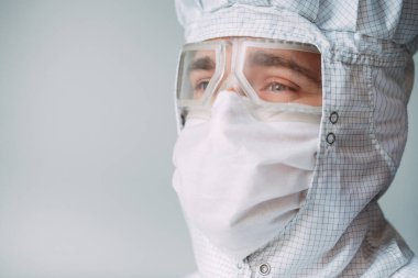 Tıbbi maske, koruyucu gözlük ve kimyasal elbise takmış Avrupalı bir erkek doktorun portresi..