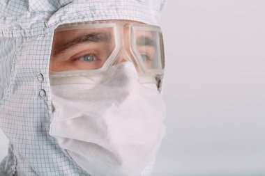 Tıbbi maske, koruyucu gözlük ve kimyasal elbise takmış Avrupalı bir erkek doktorun portresi..