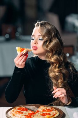 Genç ve güzel bir kız restoranda pizza yiyor..