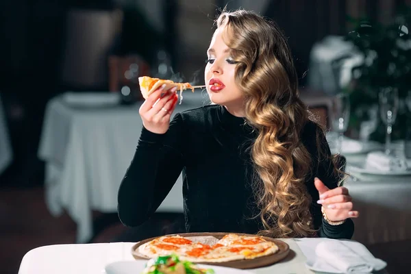 Ung vacker flicka ensam äta pizza i en restaurang. — Stockfoto