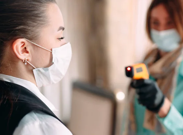 The Manager of a restaurant or hotel checks the body temperature of the staff with a thermal imaging device.