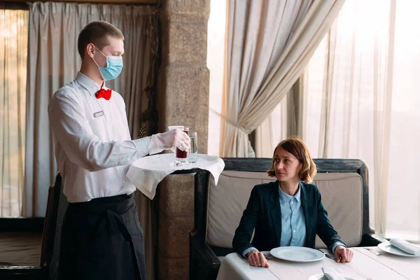 A European-looking waiter in a medical mask serves Latte coffee. — Stock Photo, Image
