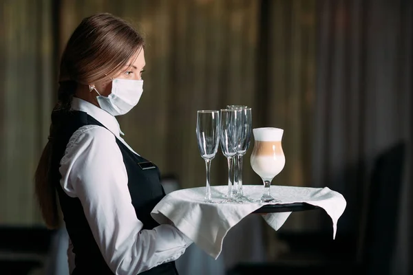 一位戴着医疗面罩的欧洲女服务员端着拿铁咖啡. — 图库照片