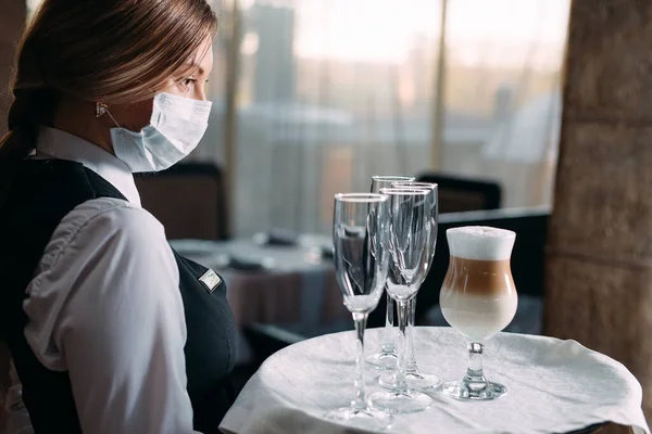 Pelayan wanita Eropa dengan topeng medis menyajikan kopi Latte.. — Stok Foto