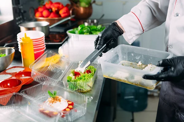 Food delivery in the restaurant. The chef prepares food in the restaurant and packs it in disposable dishes. — Stock Photo, Image