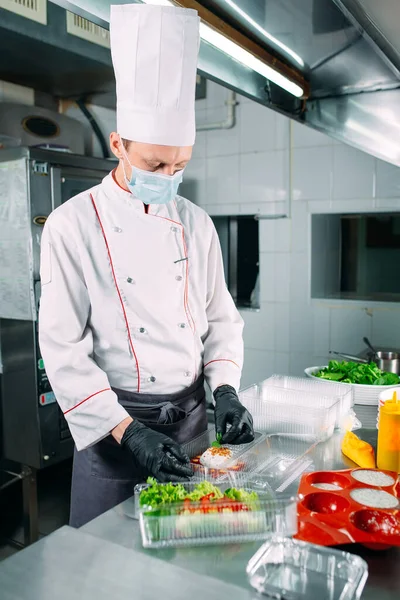 Food delivery in the restaurant. The chef prepares food in the restaurant and packs it in disposable dishes. — Stock Photo, Image