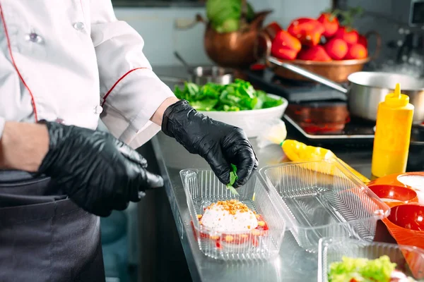 Food delivery in the restaurant. The chef prepares food in the restaurant and packs it in disposable dishes. — Stock Photo, Image