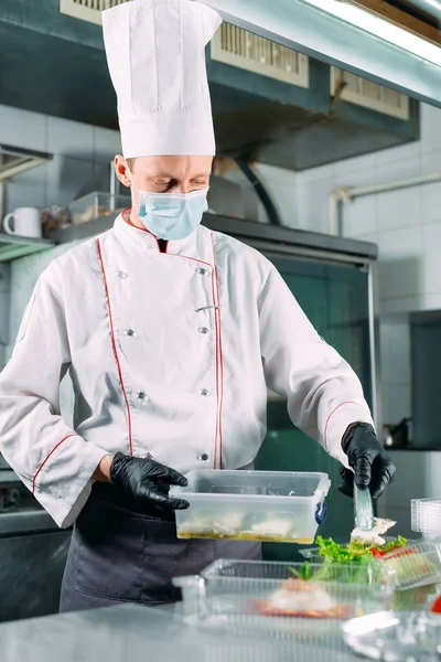 Food delivery in the restaurant. The chef prepares food in the restaurant and packs it in disposable dishes. — Stock Photo, Image